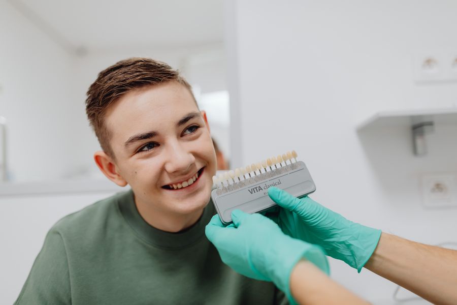 Patient smiling while a shade guide is held to his teeth
